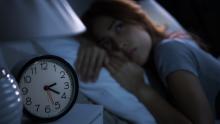Hafif aydınlıkta bir kadın yatakta yatıyor ve uzaklara bakıyor. Başucundaki komidinin üzerinde akrep yelkovanlı bir saat duruyor.