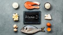 Siyah tahta üzerinde beyaz tebeşir ile vitamin D yazısı ve tahta etrafında vitamin D  içeren balık, yumurta, peynir gibi  besinlerin yer aldığı görsel