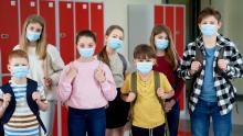 Okul koridorunda cerrahi maske takmış çocuklar.